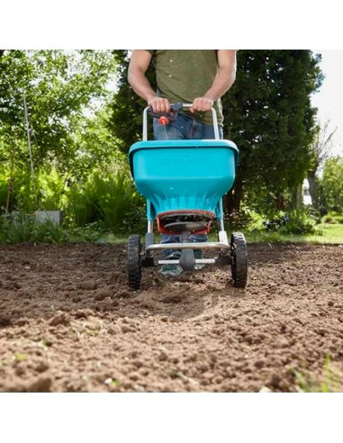 hombre en huerto labrado con carro Esparcidor XL de Gardena para semillas